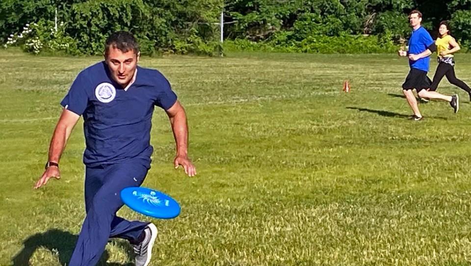 A graduate student chases a frisbee during a game